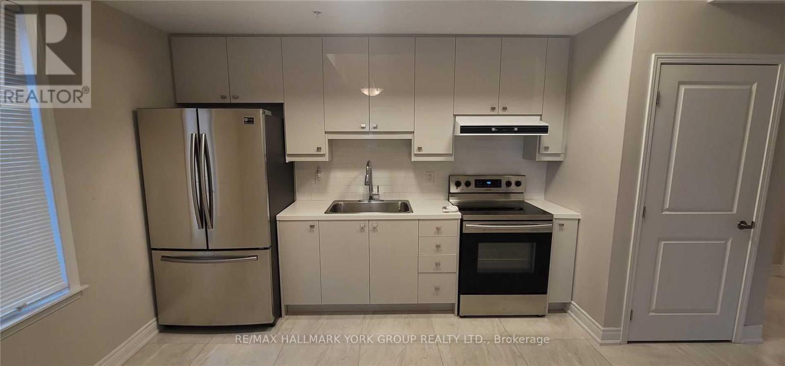 A kitchen with a refrigerator, sink, and stove.