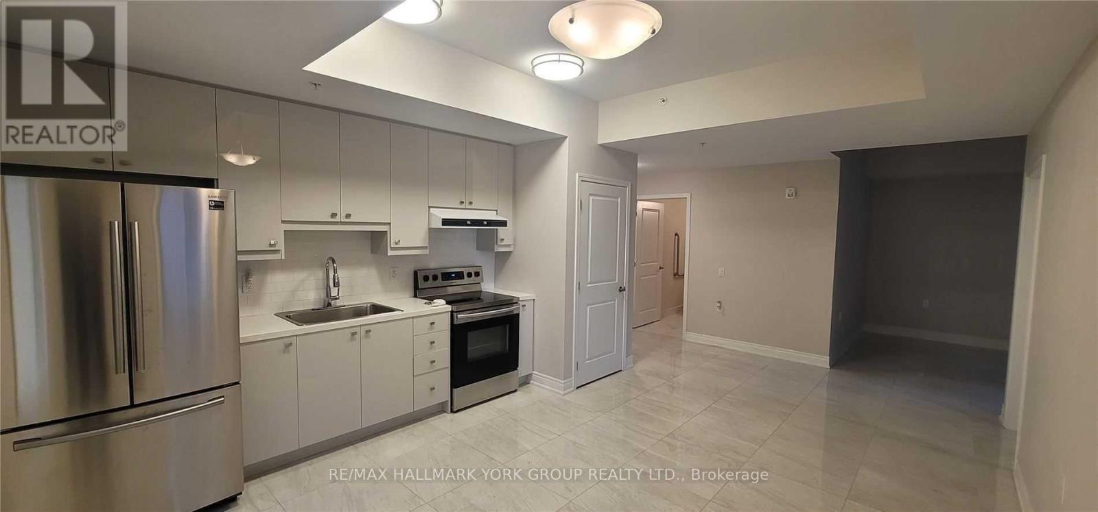 A kitchen with a refrigerator, oven, and sink.