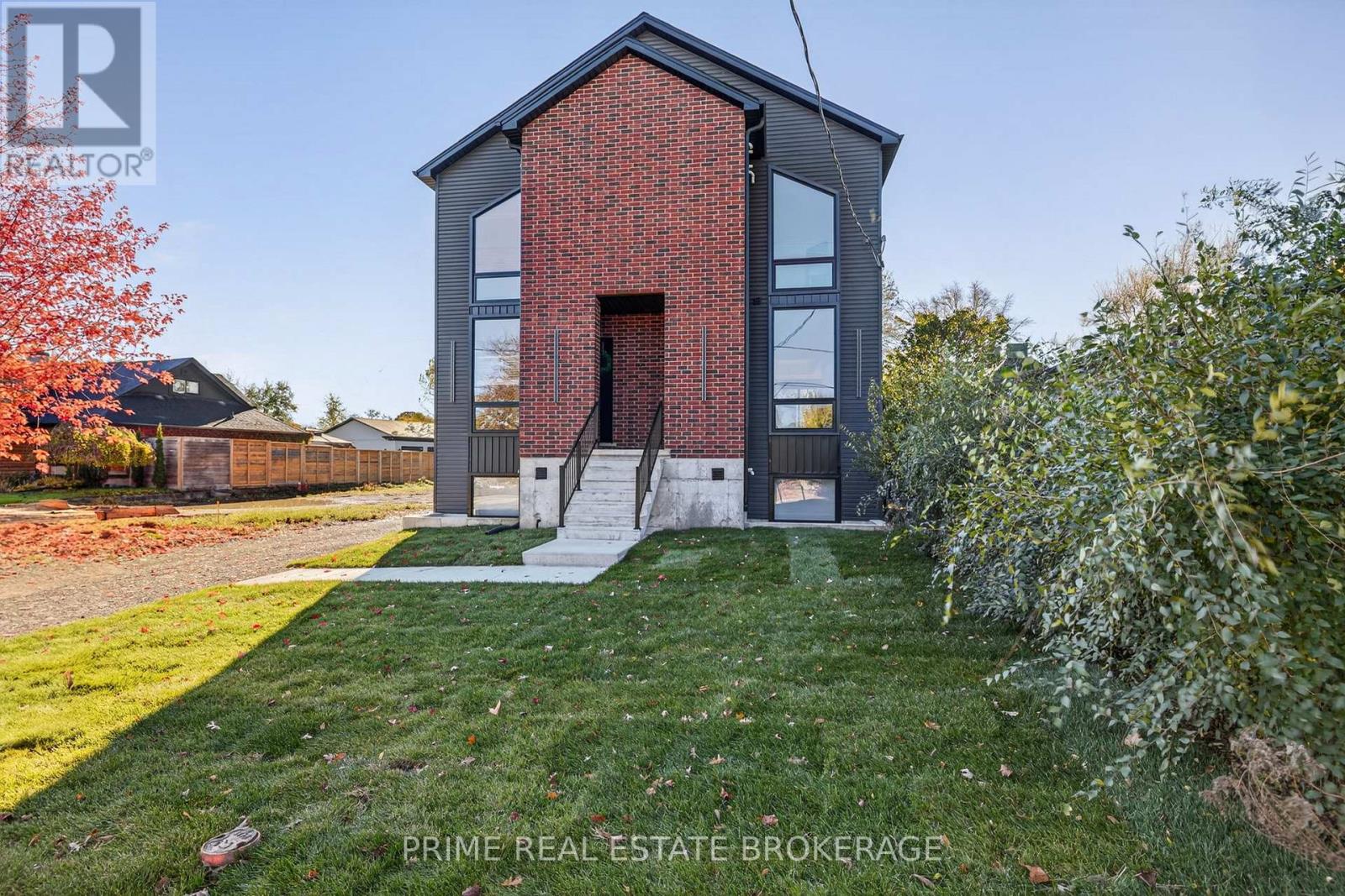 A brick house with a black roof and a white door is for sale.