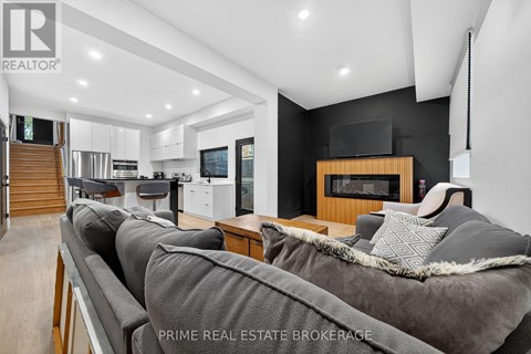 A modern living room with a grey couch and a wooden fireplace.