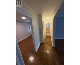 A hallway with wood floors and white walls.