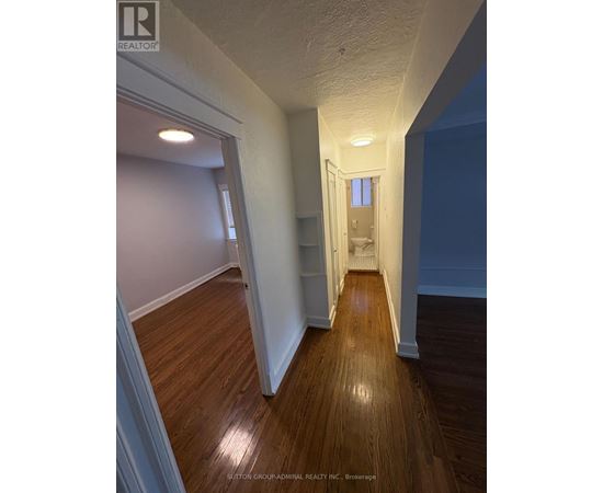 A hallway with wood floors and white walls.