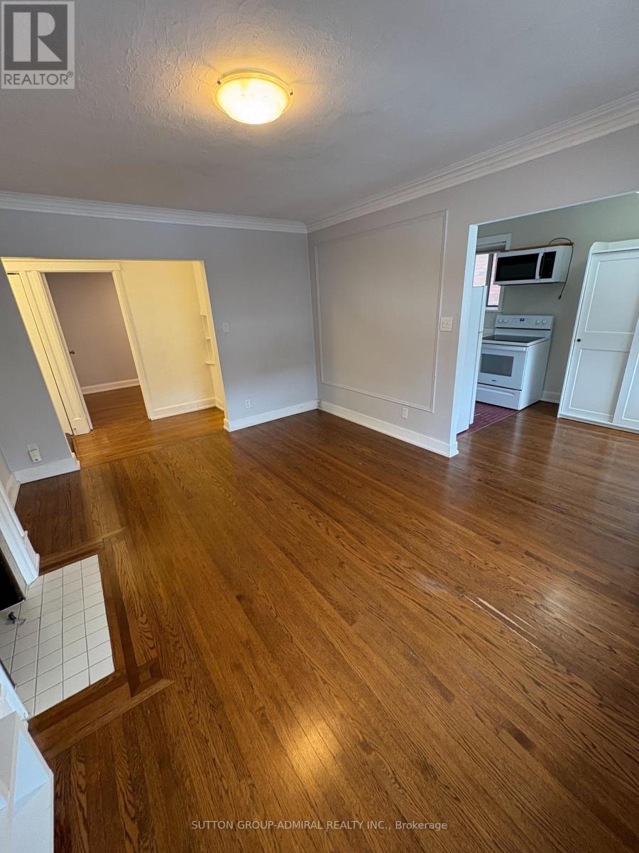 A room with wooden floors and white walls, with a doorway leading to another room.