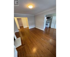 A room with wooden floors and white walls, with a doorway leading to another room.