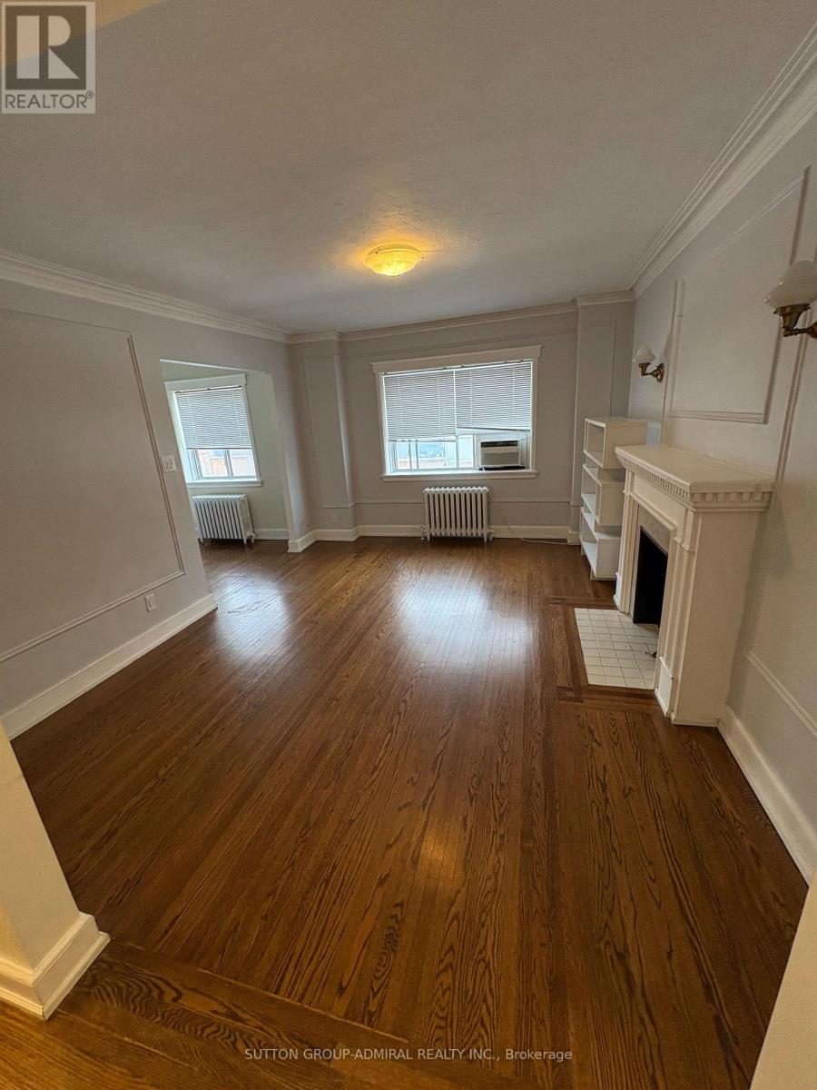 A spacious room with wood flooring and white walls.