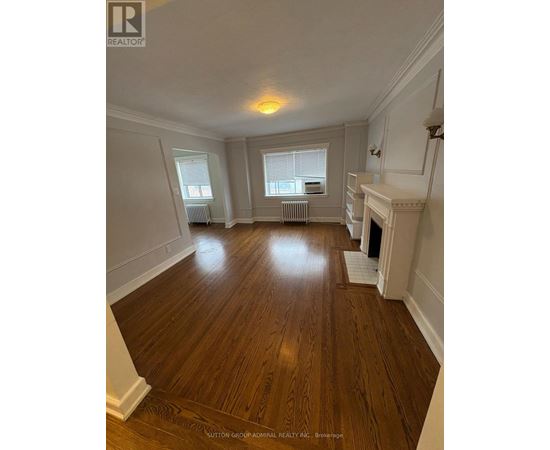 A spacious room with wood flooring and white walls.