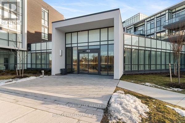 The image shows the front of a modern building with glass windows and a white entrance.