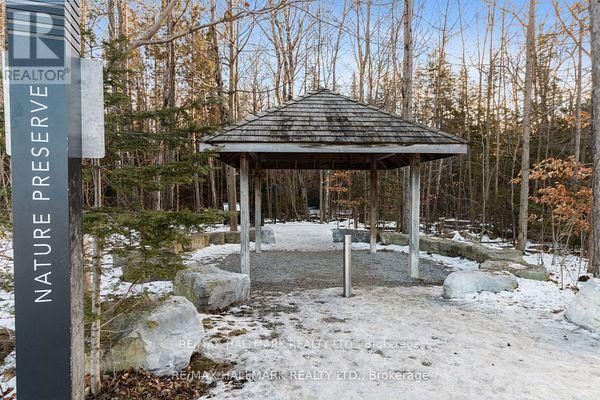 A gazebo sits in a snowy field with trees in the background.