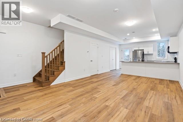 A spacious room with wooden floors and a staircase.