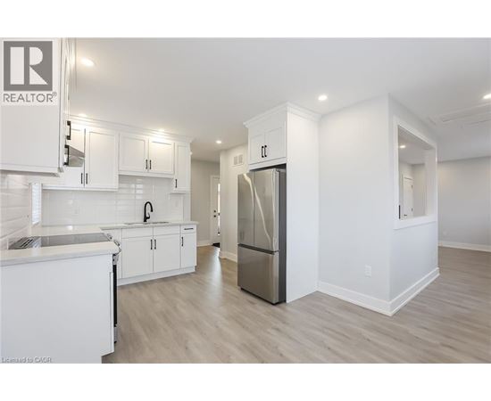 A modern kitchen with white cabinets and a refrigerator.