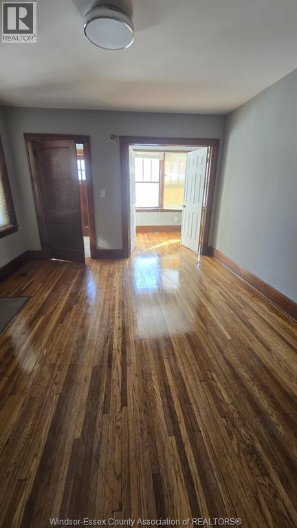 A room with wooden floors and a door leading to another room.