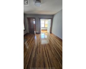 A room with wooden floors and a door leading to another room.
