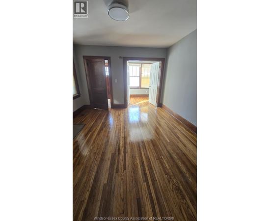 A room with wooden floors and a door leading to another room.