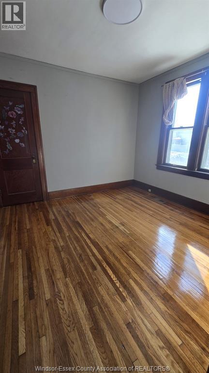 A room with wooden flooring and a window with curtains.