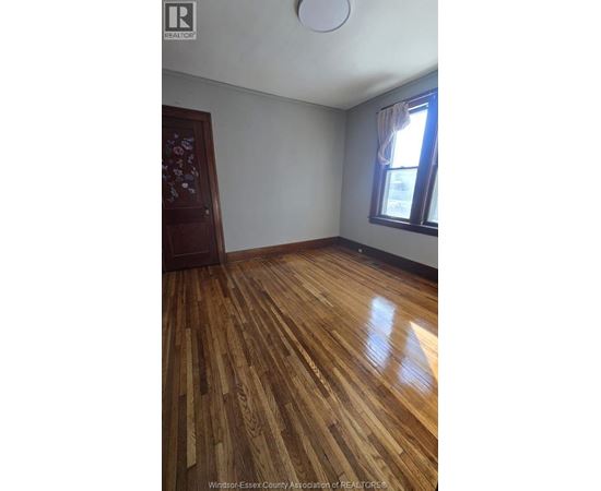 A room with wooden flooring and a window with curtains.