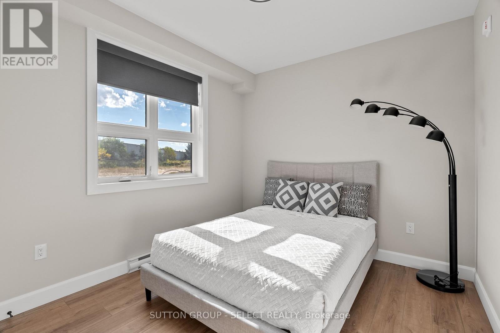 A bedroom with a large bed and a window with blinds.