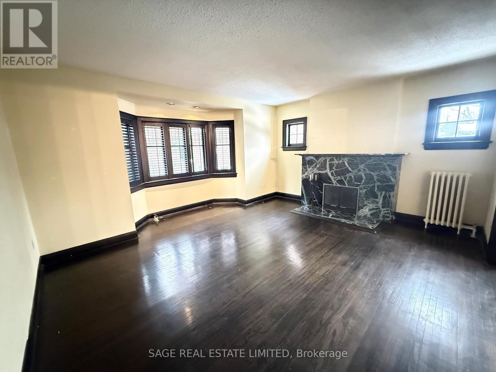 A room with wood flooring and a fireplace in the corner.