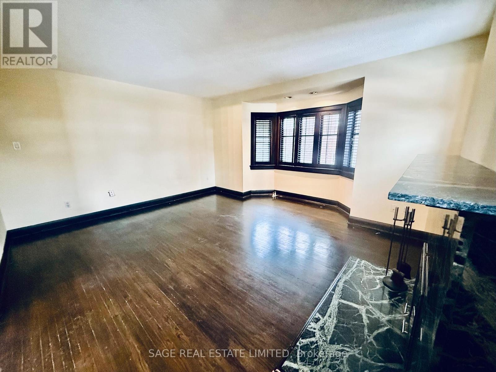 A room with wooden flooring and a window with black shutters.