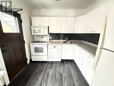 A kitchen with white appliances and black tile backsplash.