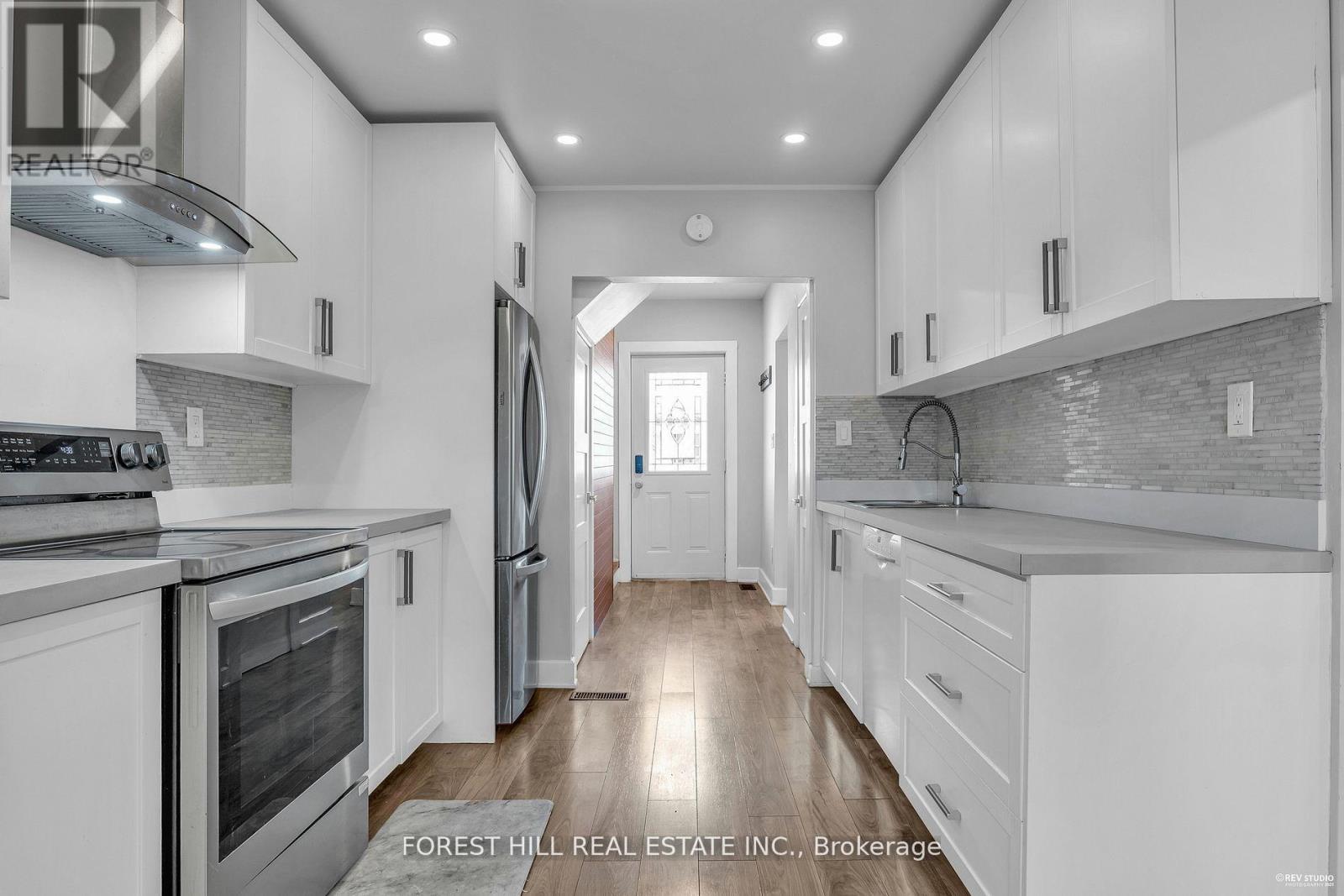 A modern kitchen with white cabinets and stainless steel appliances.
