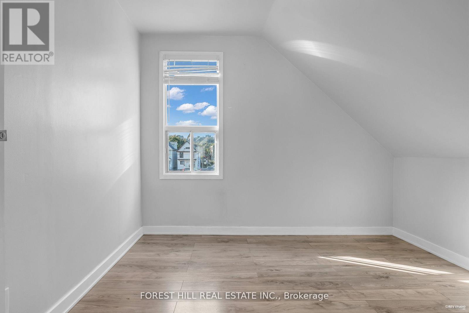 A room with a window showing a view of the sky and trees.