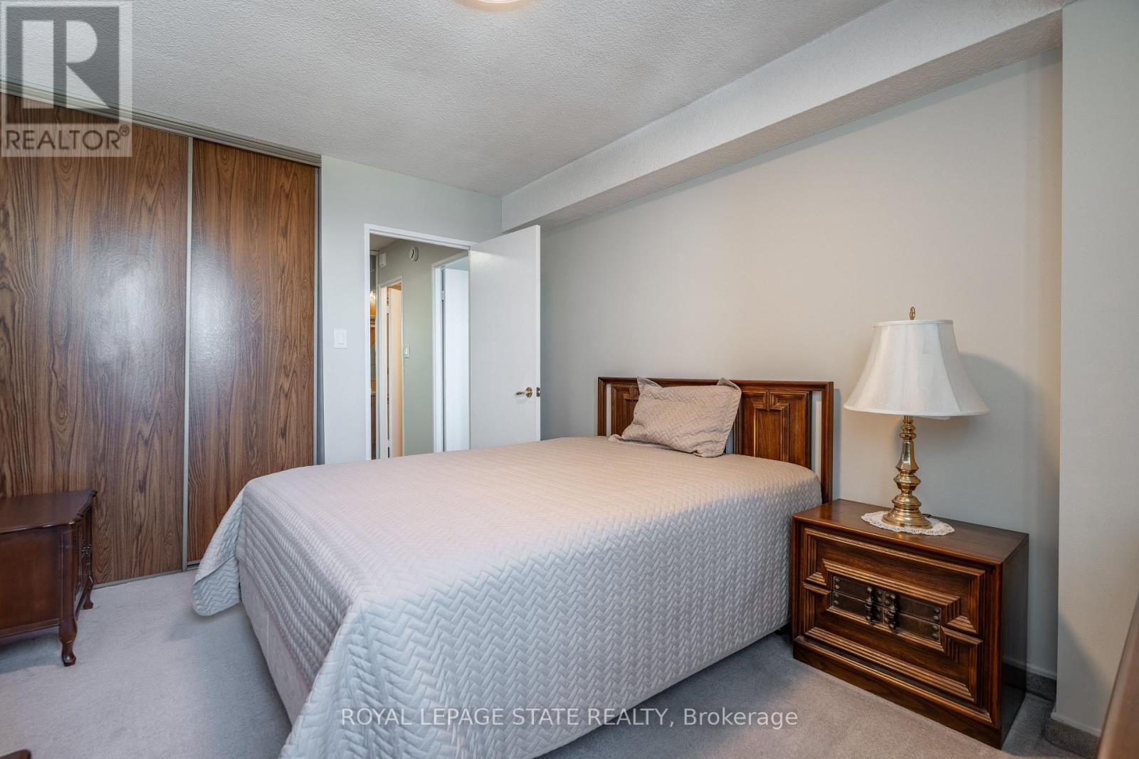 A bedroom with a bed, nightstand, and lamp.