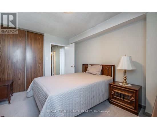 A bedroom with a bed, nightstand, and lamp.