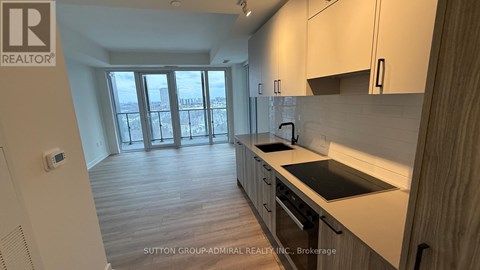A kitchen with a stove top oven and a view of the outdoors through the window.