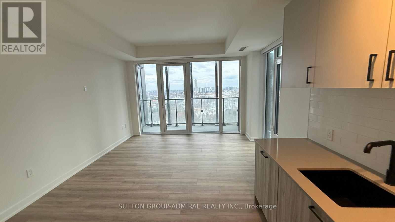 A kitchen area with a sink and a window overlooking a cityscape.