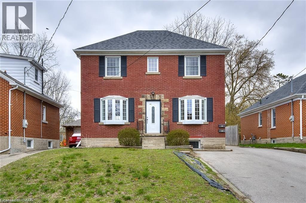 A red brick house with a white door and black shutters.