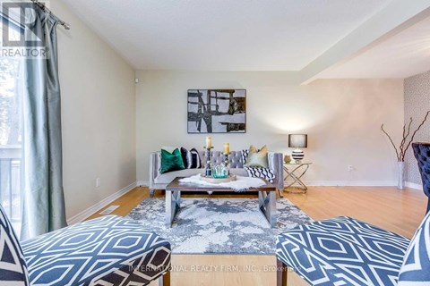 A living room with a grey and white patterned rug, a wooden coffee table, and a painting on the wall.