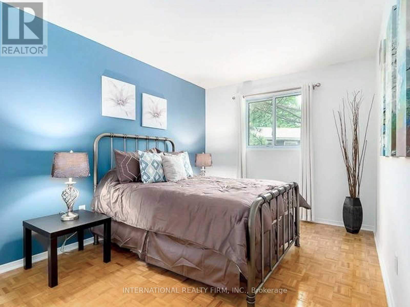 A bedroom with a bed, nightstand, and a table with a lamp on it.