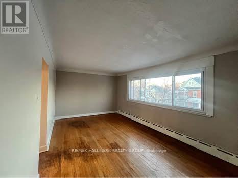 A room with wooden flooring and a window showing a view of a building outside.
