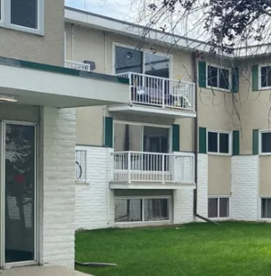 A white and beige building with a balcony.