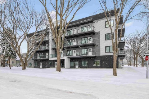 A multi-story building with balconies and a stop sign in front.