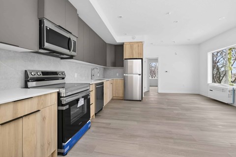 A modern kitchen with wooden cabinets and a stainless steel refrigerator.