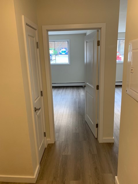 A hallway with white doors and a window.