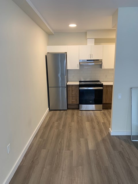 A kitchen with a stainless steel refrigerator and wooden flooring.