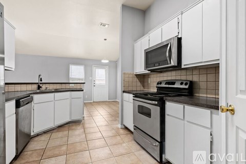 A kitchen with white cabinets and a black stove top oven.