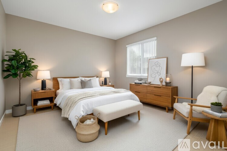 A well-lit bedroom with a large bed, a chair, and a plant.