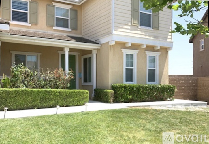 A house with a well-manicured lawn and a hedge in front.