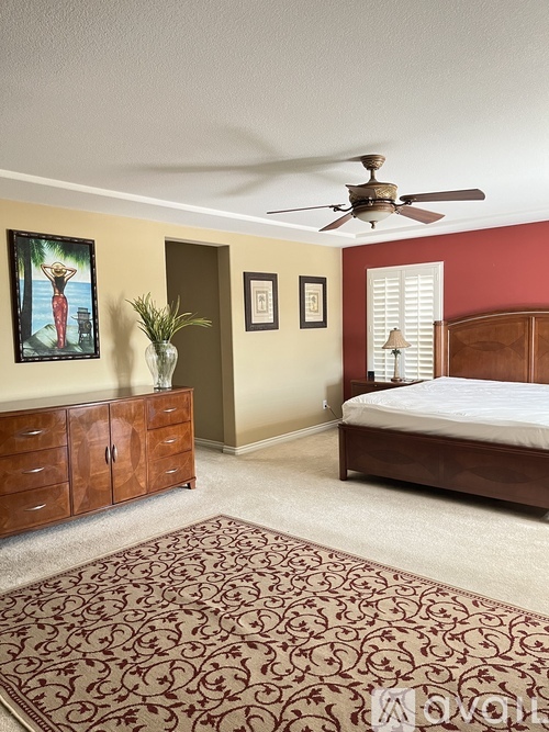 A bedroom with a bed, dresser, and ceiling fan.