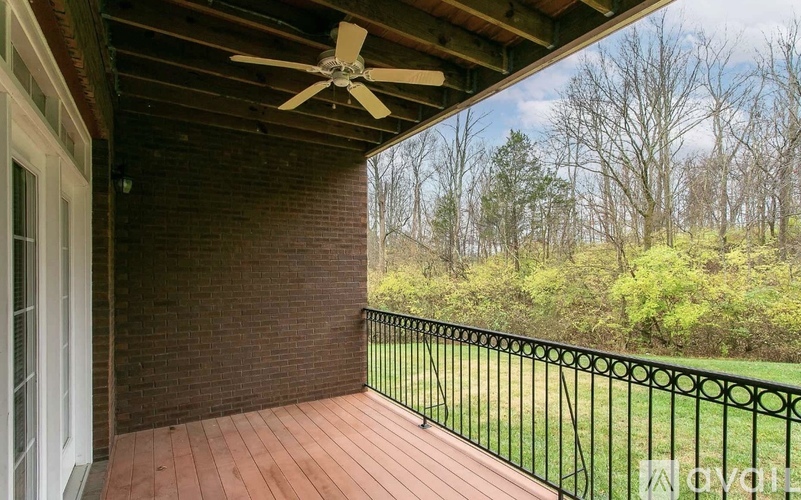 A balcony with a ceiling fan and a view of trees.