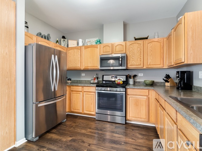A kitchen with wooden cabinets and a stainless steel refrigerator.