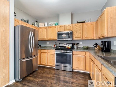 A kitchen with wooden cabinets and a stainless steel refrigerator.