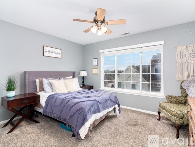 A bedroom with a bed, chair, and window.