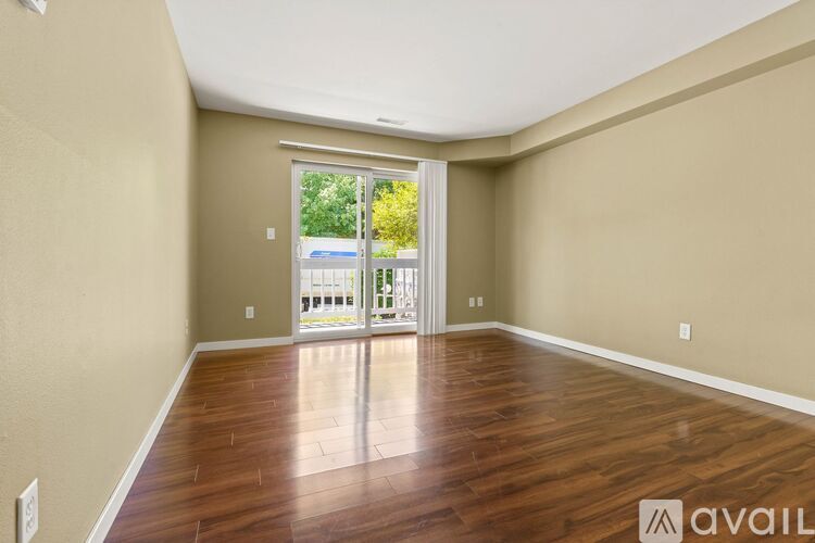 A room with wooden flooring and a sliding glass door leading to a balcony.