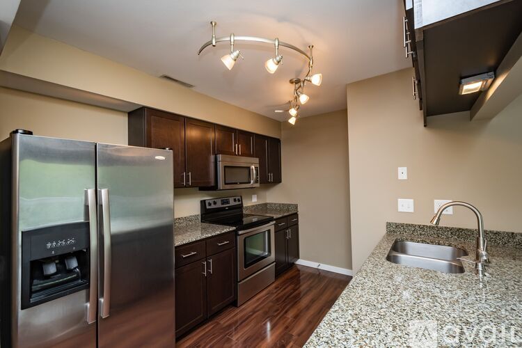 A kitchen with a refrigerator, microwave, oven, sink and cabinets.