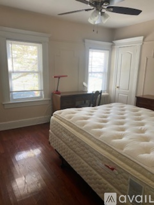A bed with a white mattress is in a room with a fan.