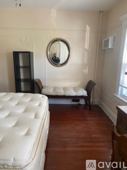 A bedroom with a white bed and a round mirror on the wall.